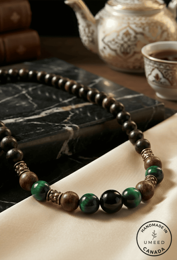 Handmade beaded necklace with green and black beads on a beige fabric background.