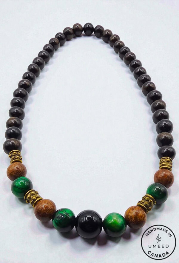 Stylish beaded necklace featuring black, green, and wooden beads with gold accents. Perfect for casu.