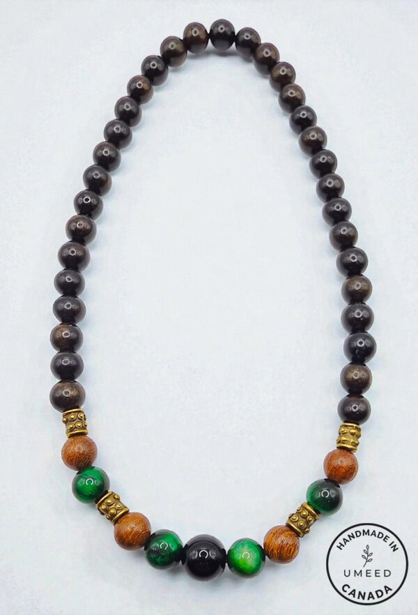 Beaded necklace featuring black, green, and wooden beads with gold accents, handcrafted in Canada.