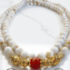Elegant pearl and gold beaded necklace with a striking red centerpiece. Perfect for sophisticated je.