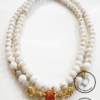 Elegant white beaded necklace with gold accents and a central orange bead, handcrafted by Umeed Desi.