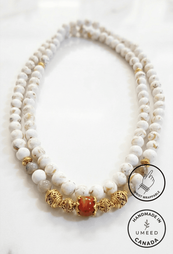 Elegant white beaded necklace with gold accents and a central orange bead, handcrafted by Umeed Desi.