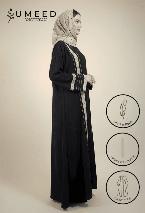 Woman wearing a black abaya with hidden zip pockets and front open design, styled with a patterned h.