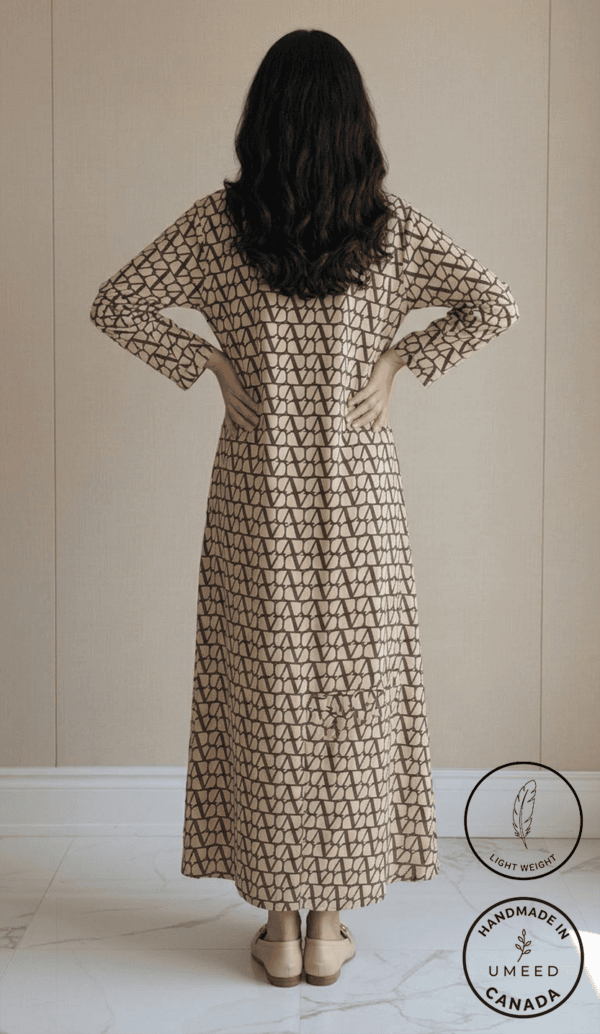 Woman wearing a beige and black geometric print maxi dress, back view.