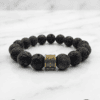 Black lava stone beaded bracelet with a gold charm accent, handcrafted by Umeed Designs.