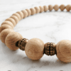 Elegant handmade wooden beaded necklace with natural wood and metallic accents.