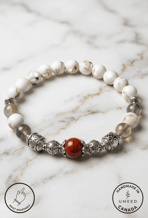 Handmade pearl and gemstone beaded bracelet on marble surface.