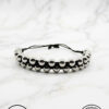 Elegant black and silver beaded bracelet with adjustable cord on marble background.