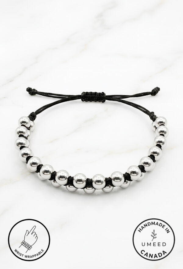 Handmade beaded bracelet with black and silver beads on a white marble background.