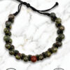 Handmade beaded bracelet with green and red stones on marble background.