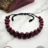 Handmade purple beaded bracelet on marble surface with Umeed Designs logo.