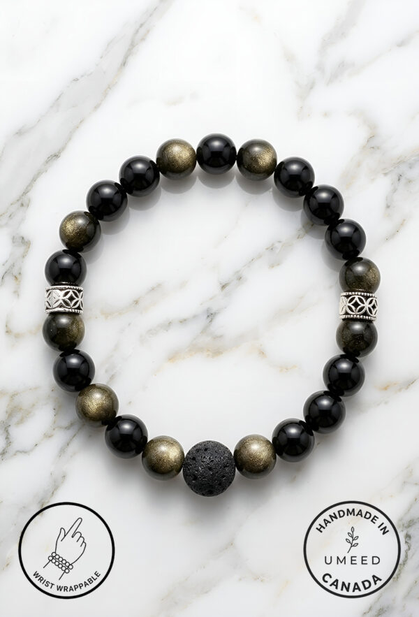Black and gold beaded bracelet with a lava stone centerpiece on a white marble background.
