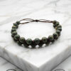 Handmade beaded bracelet with adjustable cord on marble surface.