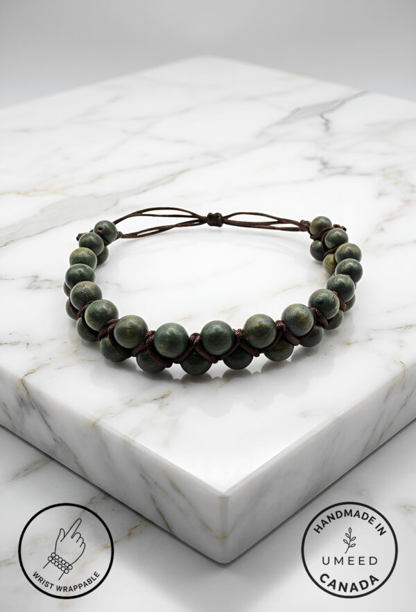 Handmade beaded bracelet with adjustable cord on marble surface.
