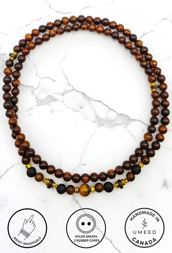 Elegant handmade wooden beaded necklace with gold accents on white marble background.