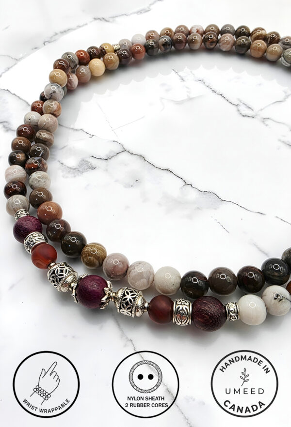 Colorful beaded necklace with silver accents on white marble background.