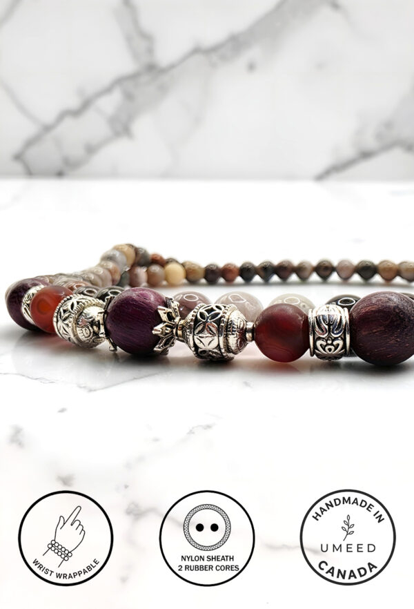 Handmade beaded necklace with silver accents on marble surface.