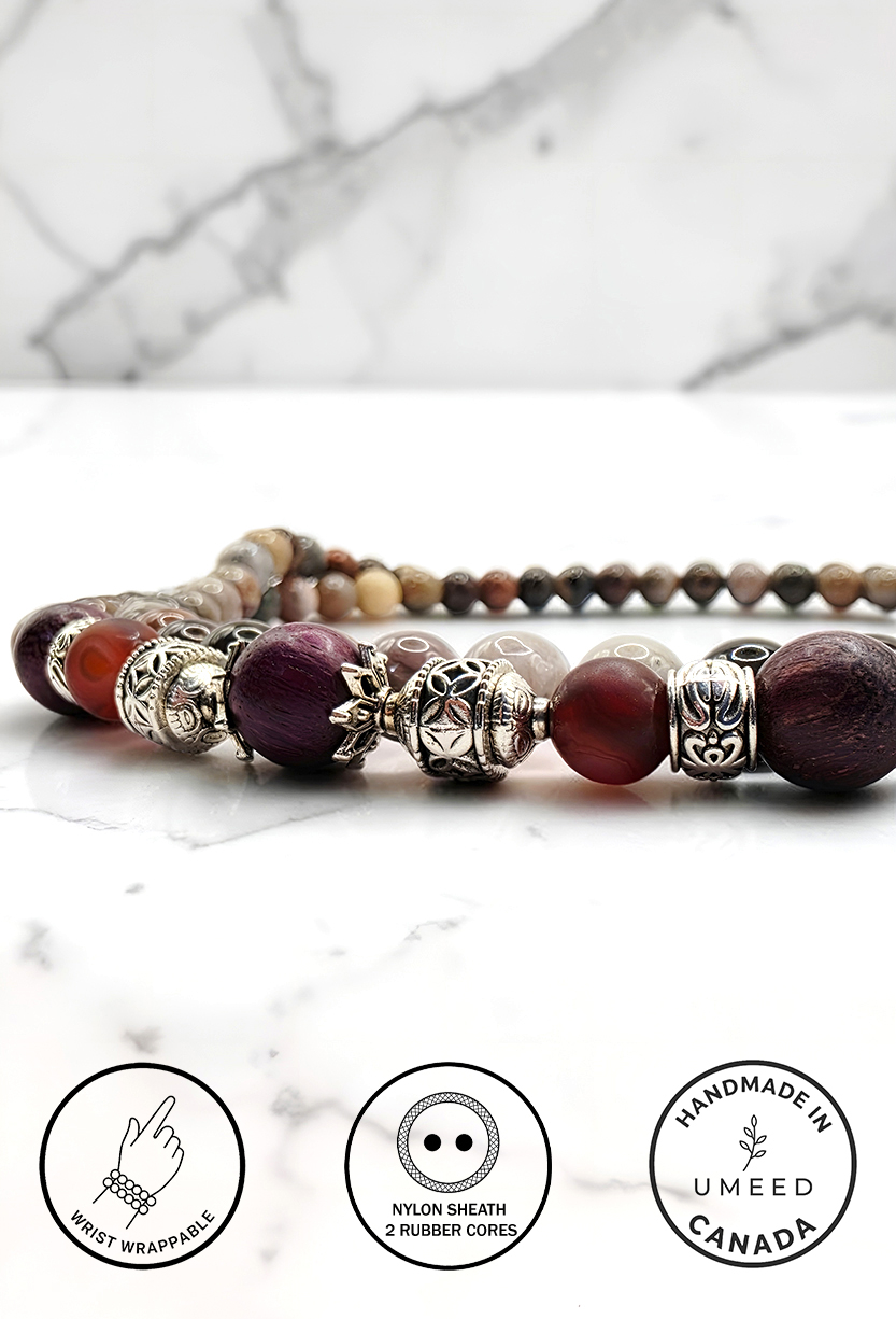 Handmade beaded necklace with silver accents on marble surface.