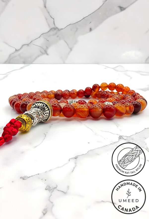 Handmade red and orange beaded bracelet with silver accents on marble background.