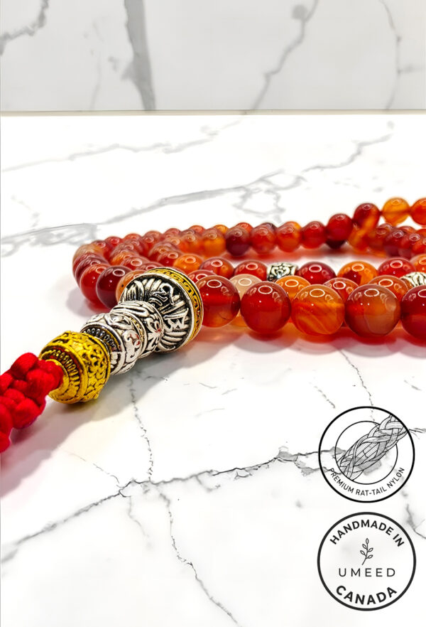 Elegant red and orange beaded necklace with silver accents on marble surface.