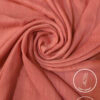 Lightweight coral pink fabric with a soft, flowing texture for elegant clothing.