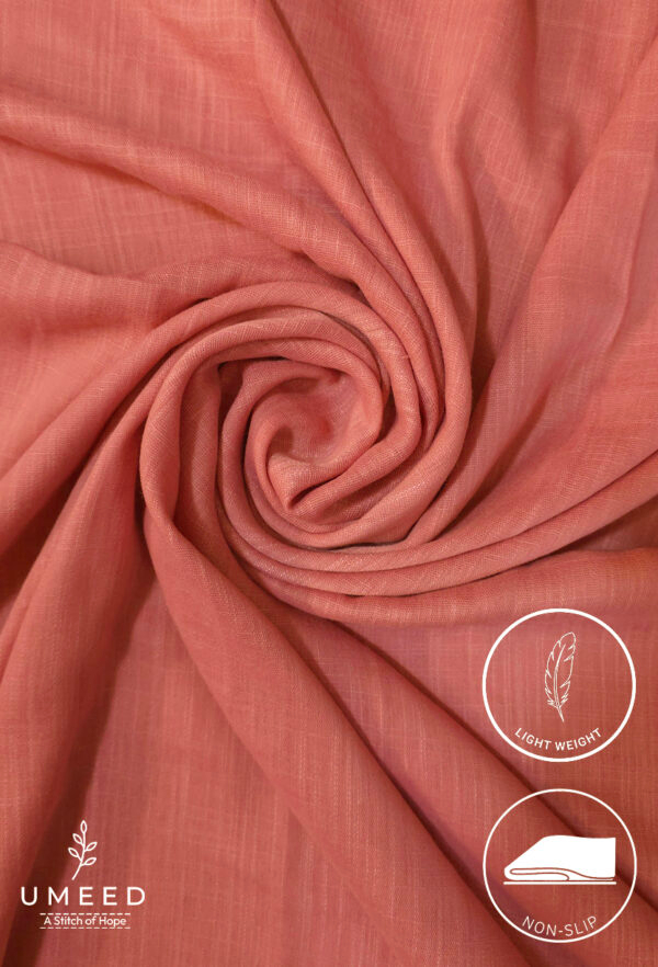 Lightweight coral pink fabric with a soft, flowing texture for elegant clothing.