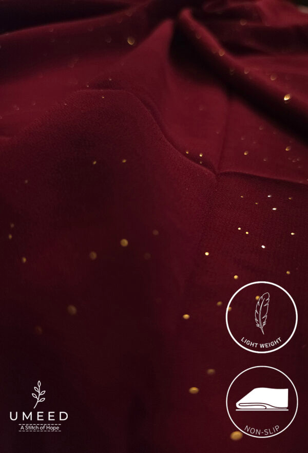 Deep red fabric with gold specks, lightweight and non-slip for elegant clothing.