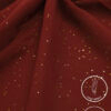 Red fabric with gold glitter accents, lightweight and non-slip for elegant clothing.