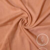 Lightweight, non-slip peach-colored fabric for clothing or crafts.