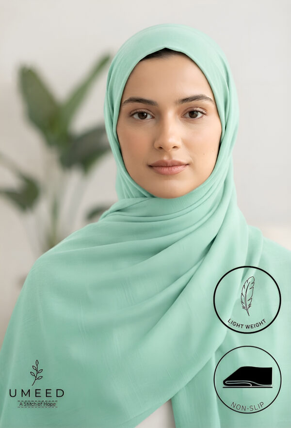 Elegant woman wearing light green hijab with natural background.