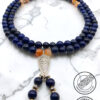 Elegant blue and gold beaded necklace with intricate pendant on marble background.