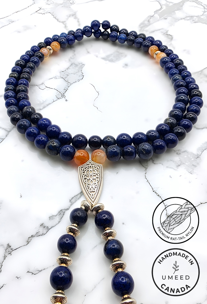 Elegant blue and gold beaded necklace with intricate pendant on marble background.