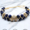 Handmade beaded bracelet with navy and beige stones on marble surface.
