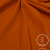 Orange lightweight, non-slip fabric with subtle glitter for elegant fashion designs.