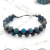 Handmade blue and gray beaded bracelet on white marble surface.