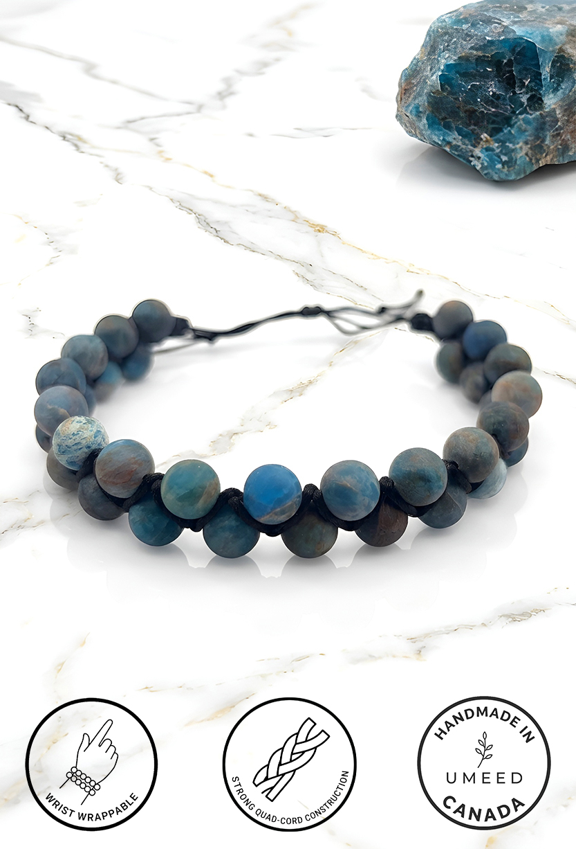 Handmade blue and gray beaded bracelet on white marble surface.