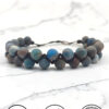 Handmade blue and gray beaded bracelet from Umeed Designs on marble surface.