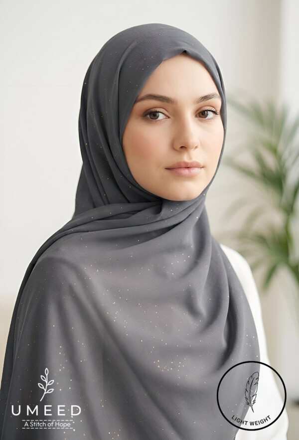 Elegant woman wearing a dark gray hijab with subtle gold accents.