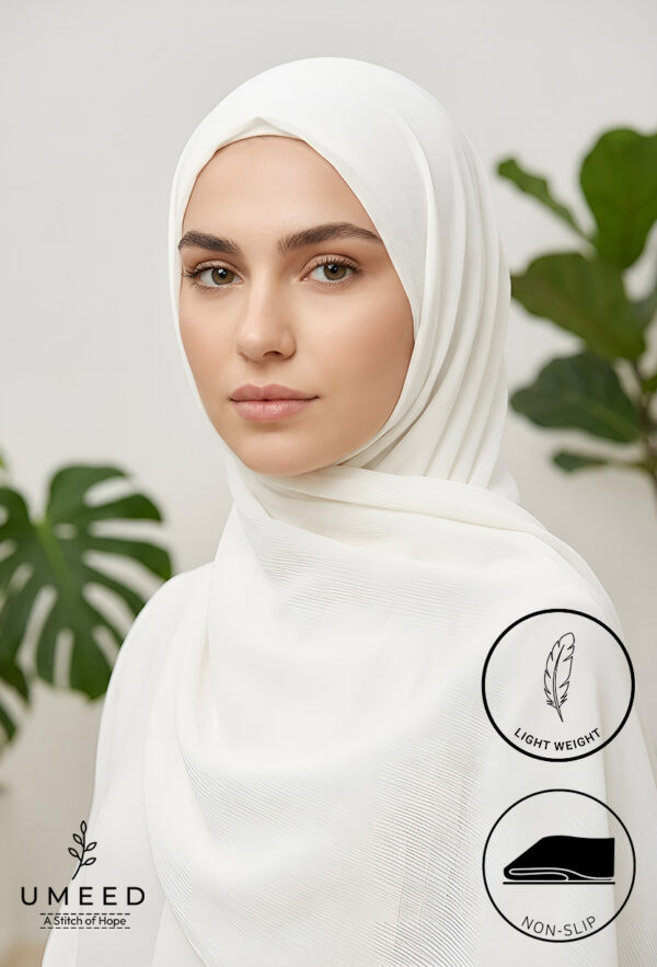 Elegant woman wearing a white hijab with green plant background.
