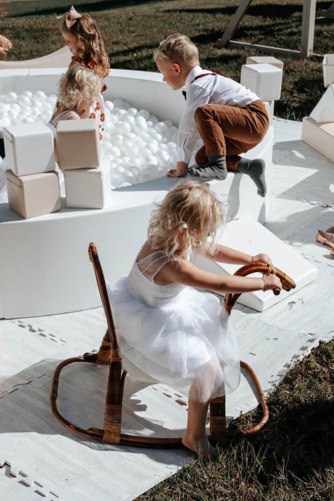 Children playing in a white ball pit at an outdoor event, capturing joyful moments among kids.
