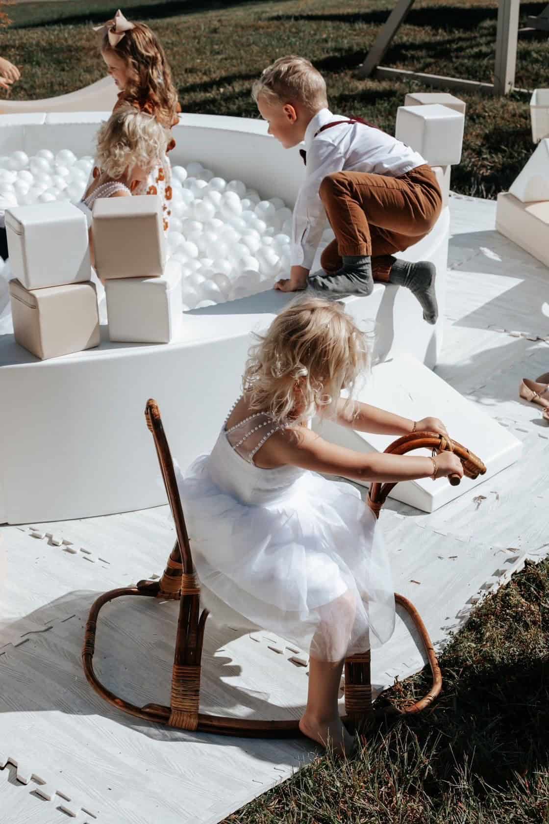 Children playing in a white ball pit at an outdoor event, capturing joyful moments among kids.