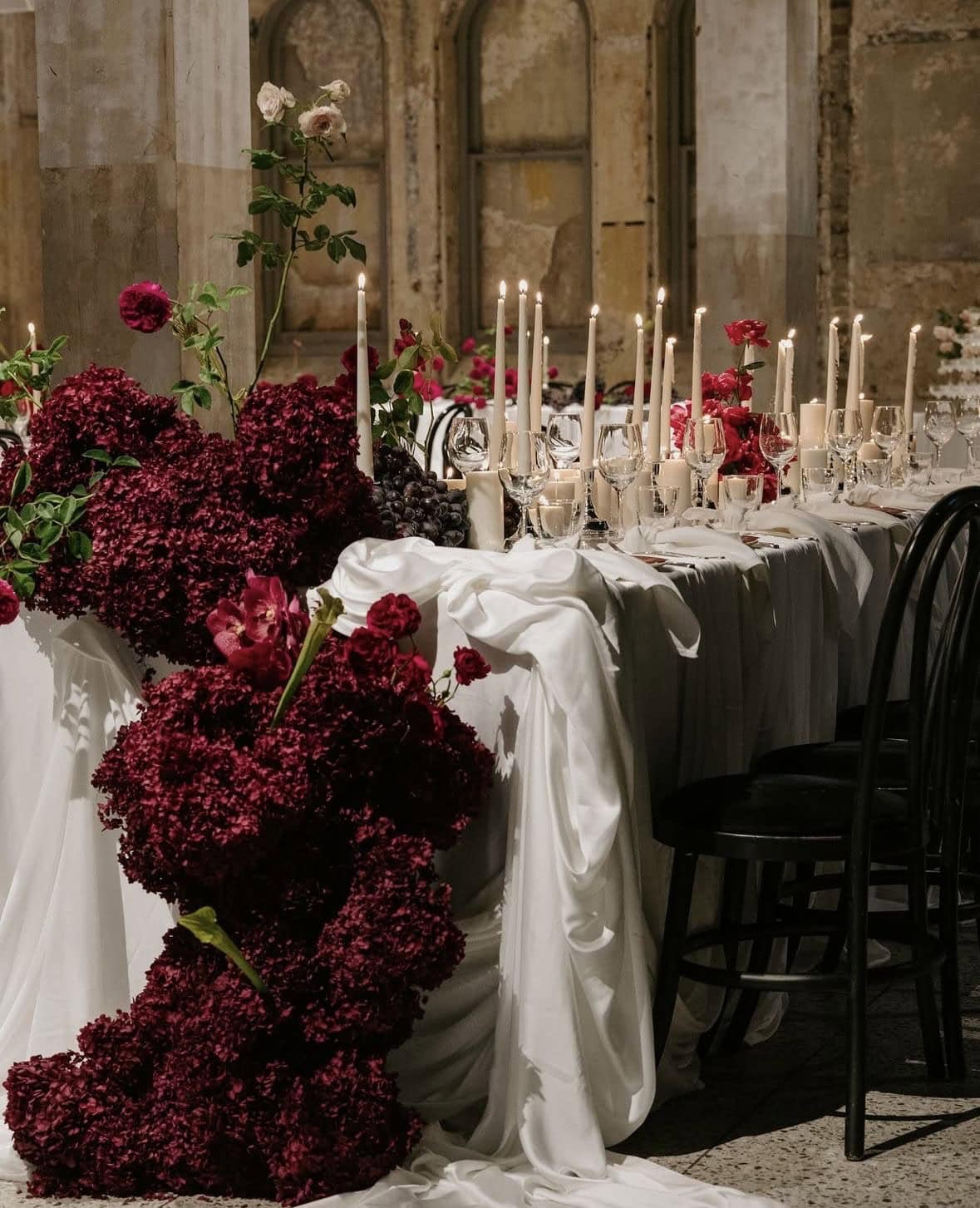 Elegant wedding table with red flowers and candles for upscale event.