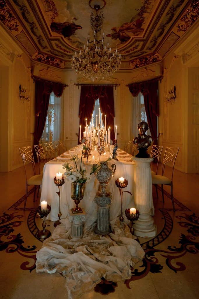 Elegant banquet table in a luxurious, classical style with candles and ornate decor.