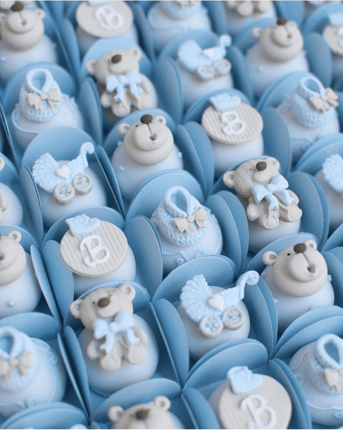 Cream-colored teddy bear and baby-themed cupcake decorations in blue fondant.
