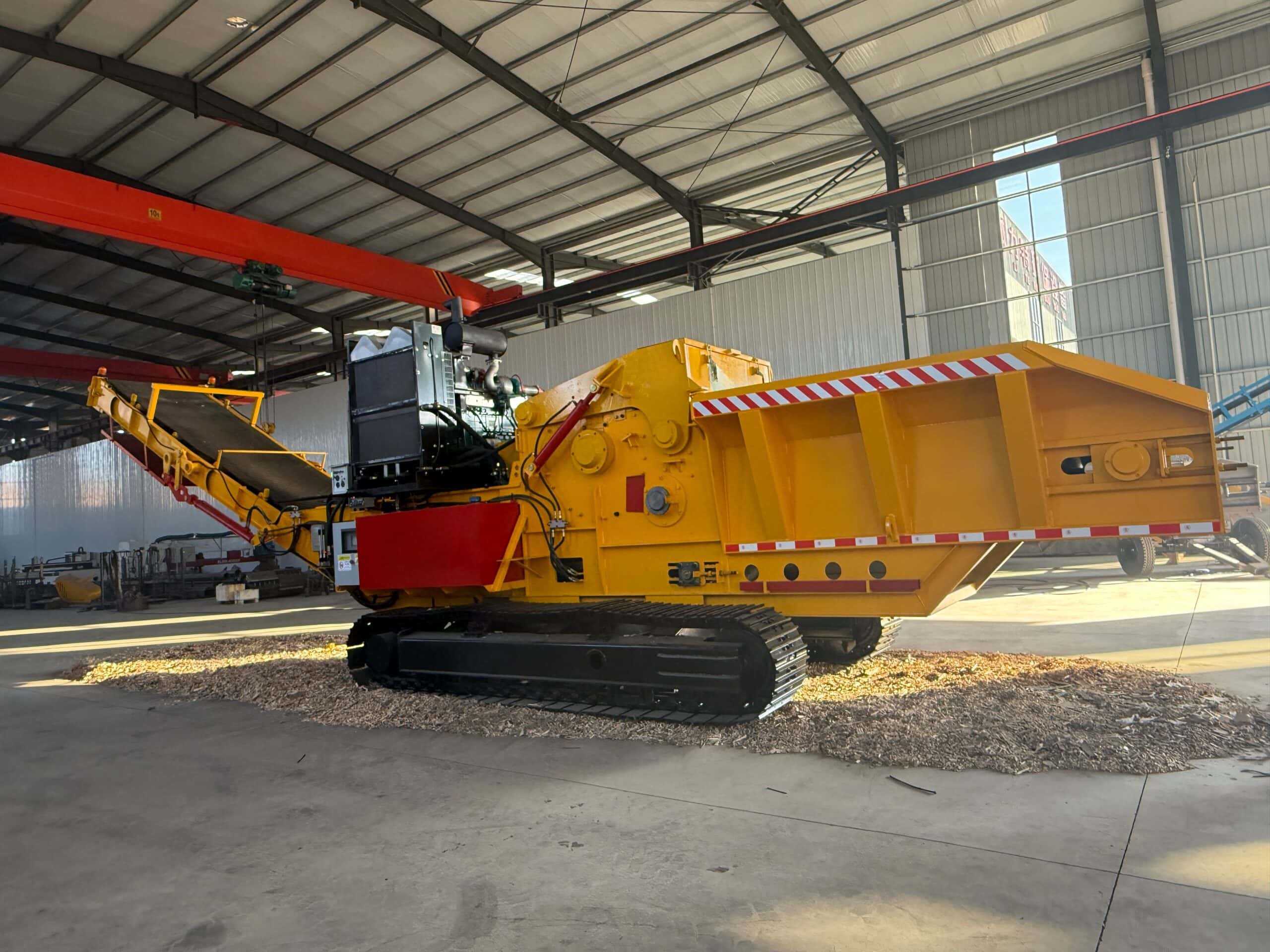 UPSEN 1300 horizontal grinder with tracked chassis and discharge conveyor on a factory floor.