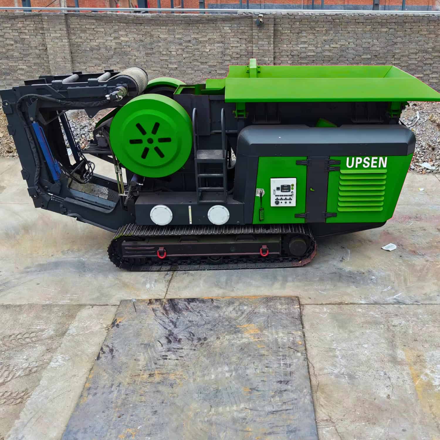 Side view of a UPSEN 704 jaw crusher with its control panel and folded conveyor visible.