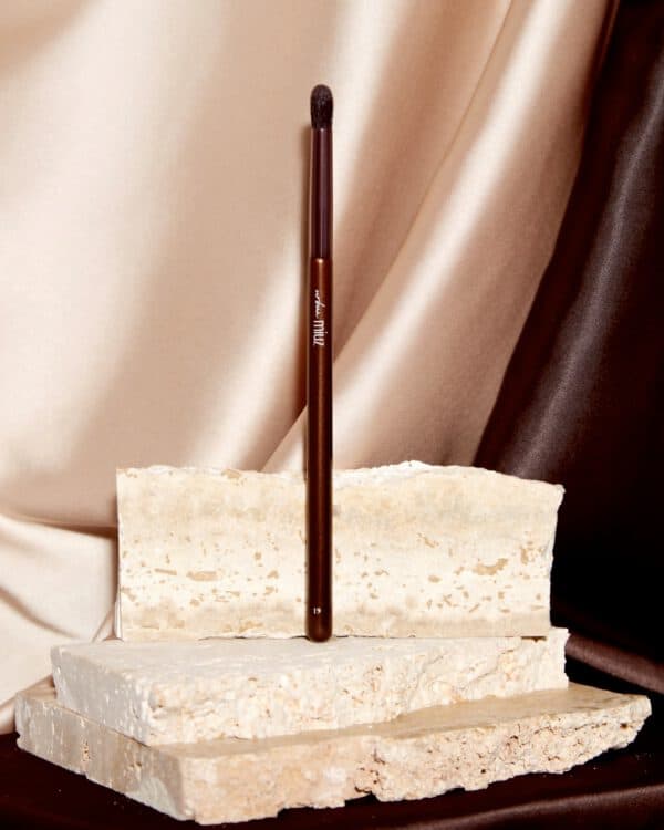 Vopsea de ochi și pensulă așezate pe pietre naturale pentru machiaj și artă.