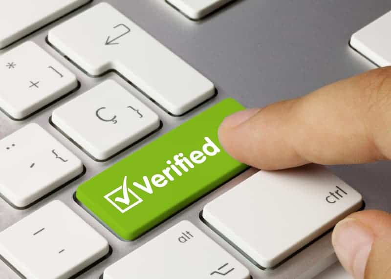 A finger pressing a button on a keyboard labelled verified
