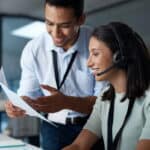 Two agents looking at a script while one is talking into a headset