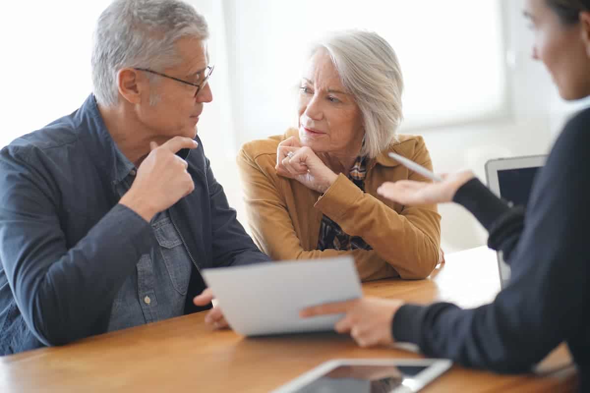 A senior couple with an insurance agent looking over some paperwork